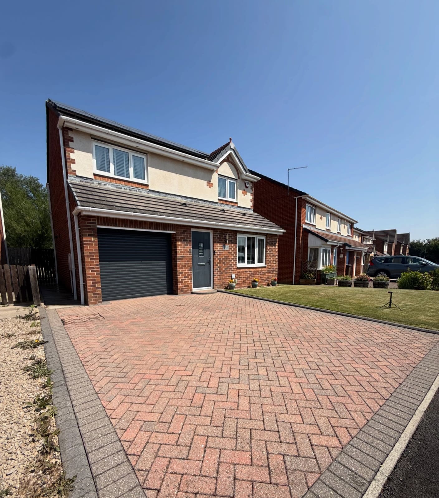 A large clean block-paved driveway in front of a detached house